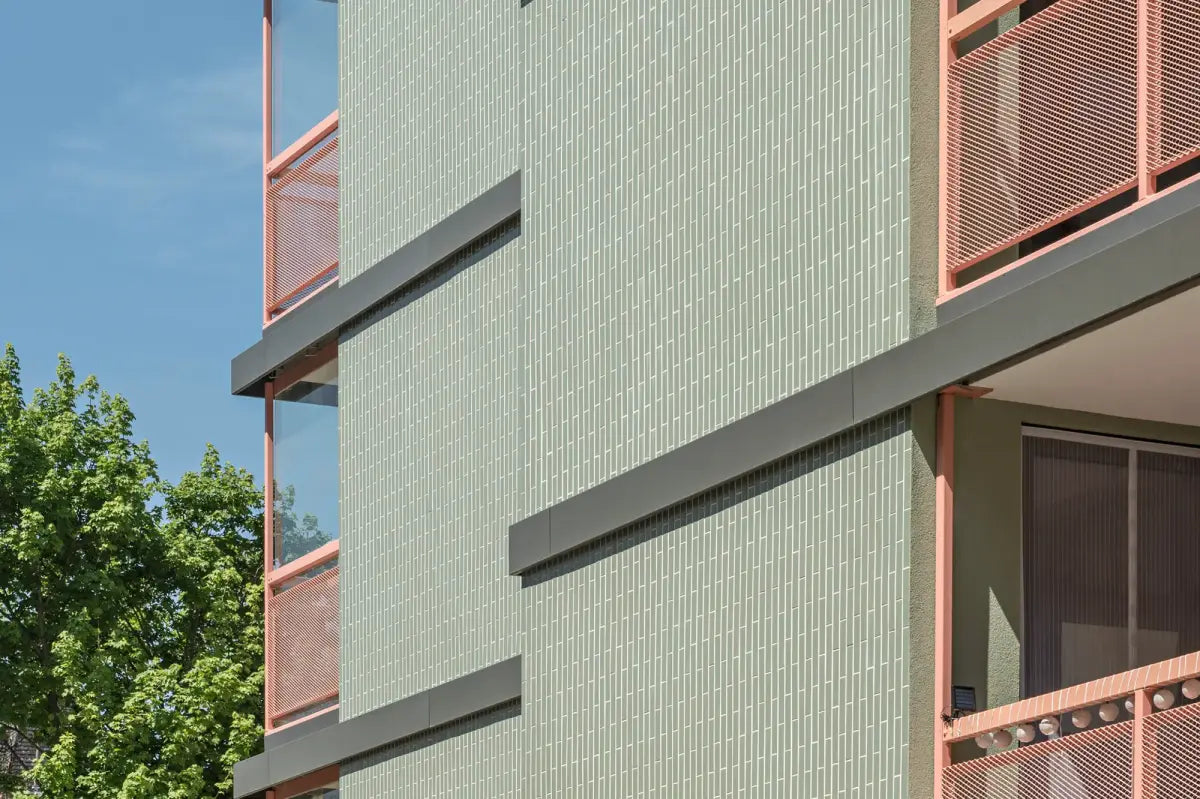 Exterior view of a modern apartment building clad in green StoVentec ceramic panels, highlighting ventilated facade performance and vibrant architectural design.