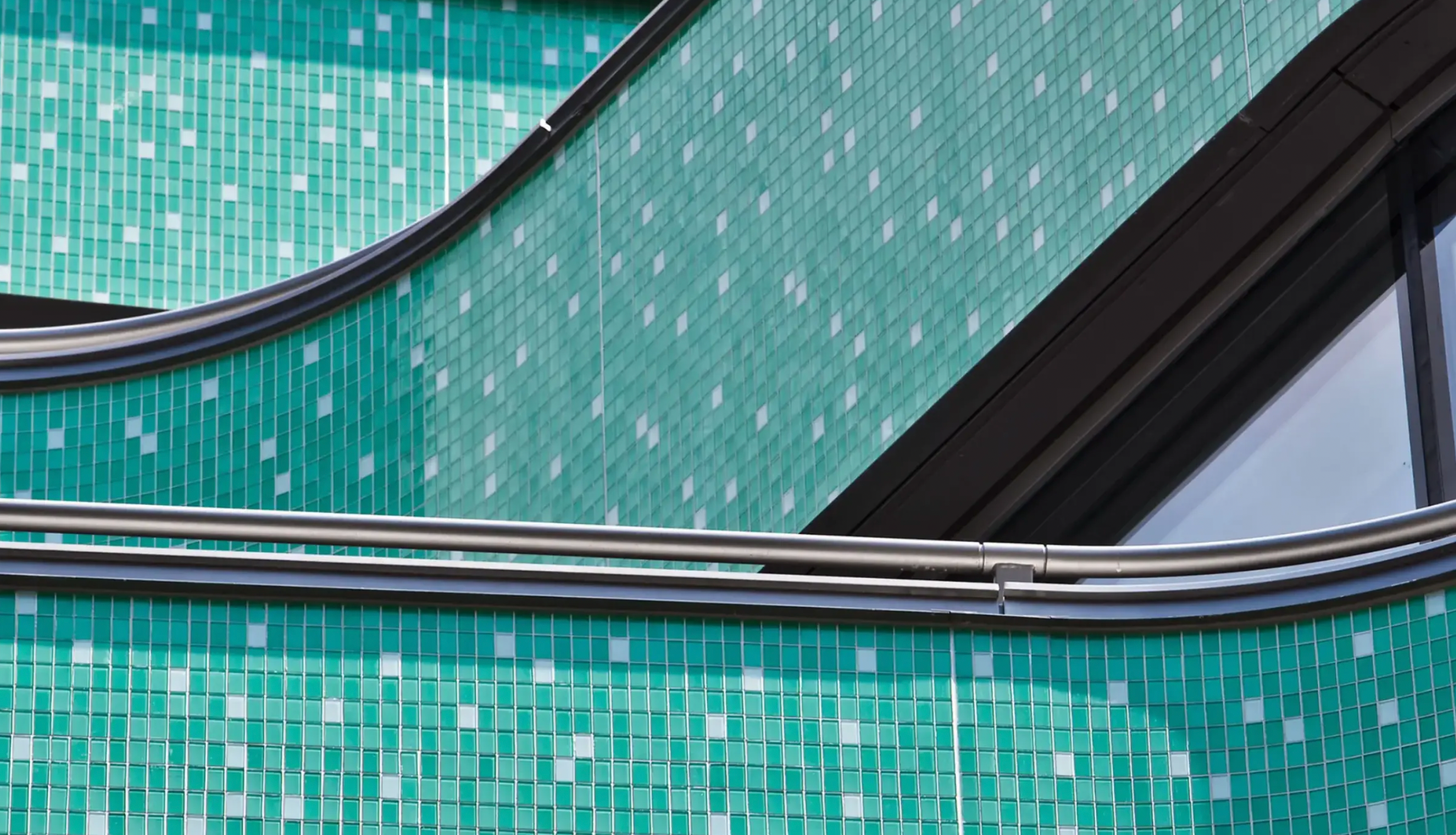 Close-up image of Sto glass mosaic in aqua color highlighting intricate tile details on swerving, tiered balconies, showcasing vibrant, durable rainscreen cladding with superior weather resistance for Atlantic Canada exteriors.