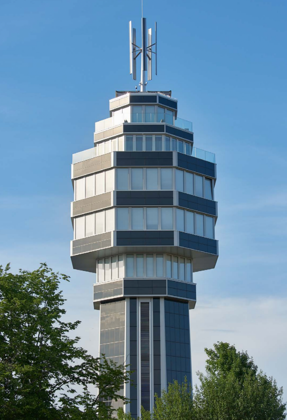 Tall commercial tower clad with StoVentec photovoltaic solar power panels, showcasing energy-efficient rainscreen system for sustainable urban architecture.