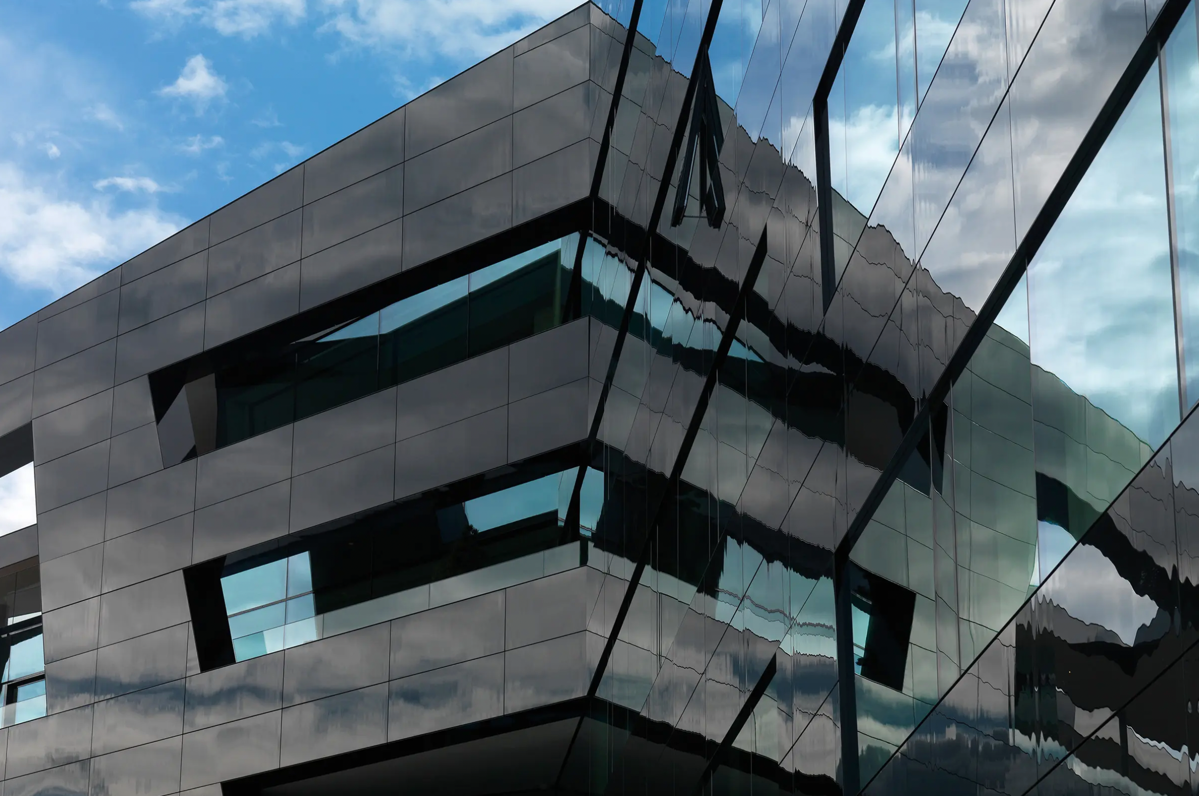 Detail image of StoVentec rainscreen system with black glass panel finish reflecting the sky, showcasing a sleek, high-performance exterior cladding solution.