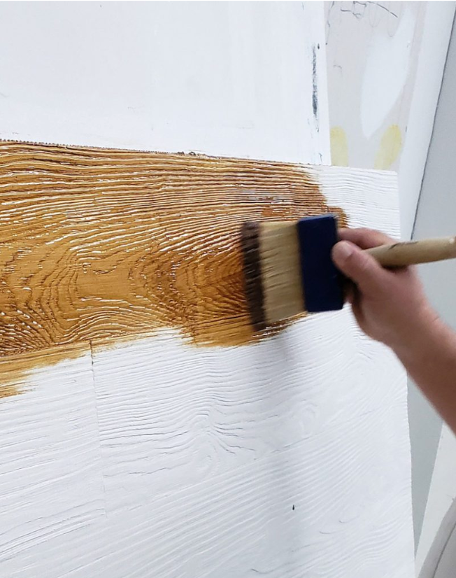 Stocast wood cladding on wall being stained with brush white