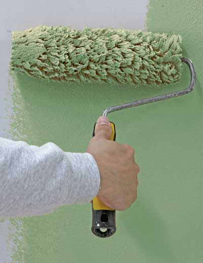 StoColor Silcolastic elastomeric paint being applied with roller, showing flexible waterproof coating installation on wall surface