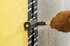 StoGuard conformable self-adhesive membrane being pressed down with hard rubber roller to ensure proper adhesion on exterior wall surface during installation