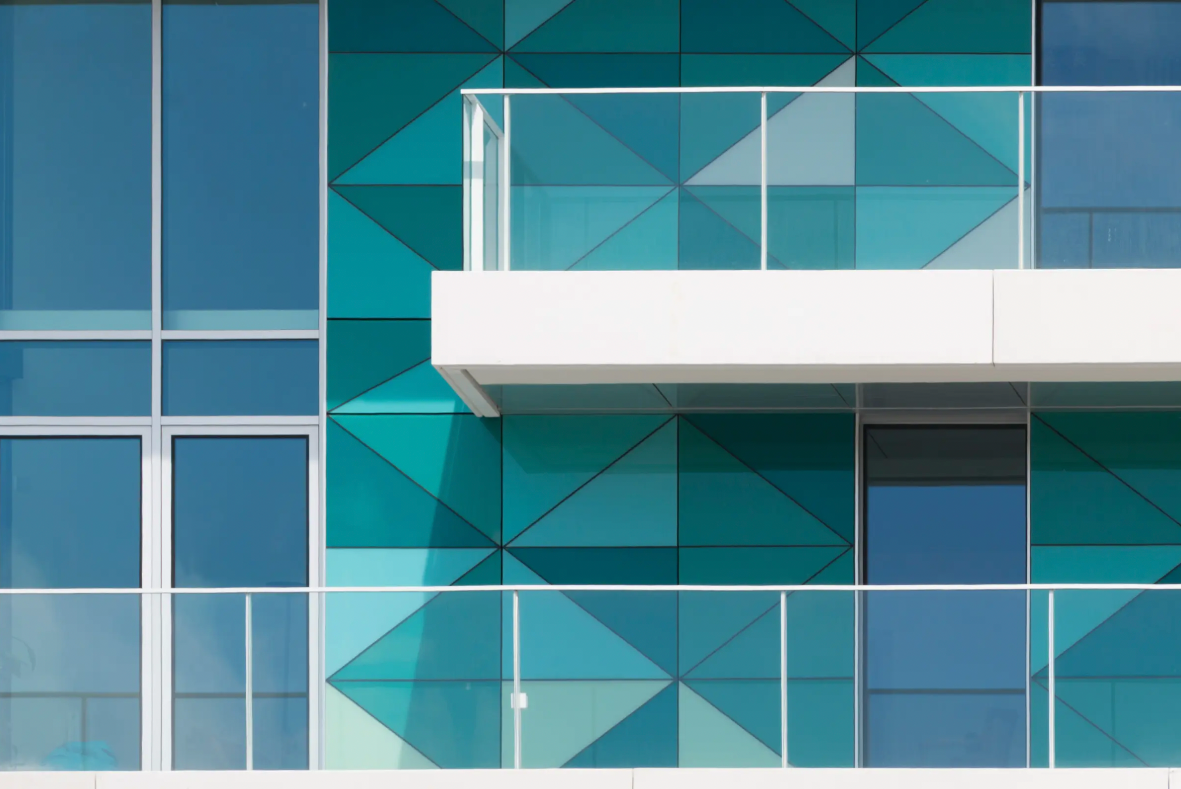 Close-up of StoVentec glass panel featuring varying shades of blue in a geometric triangle cell shaded pattern on a rainscreen facade